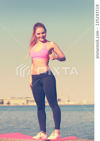 Woman in sportswear standing on dyke by sea 135293519