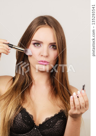 Woman applying rouge with brush to her face Woman applying rouge with brush to her face 135293541