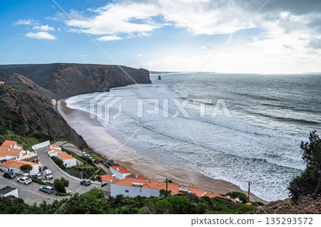 Praia da Arrifana beach framed by high cliffs on the wild west coast of Portugal - very popular beach with surfers 135293572