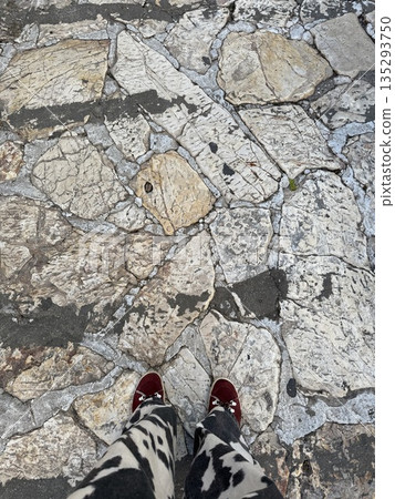 Cobblestone texture background with feet wearing red shoes visible at the bottom of the frame 135293750