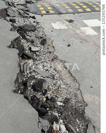 Damaged asphalt road with cracked surface showing exposed gravel and debris Damaged asphalt road with cracked surface showing exposed gravel and debris 135293766