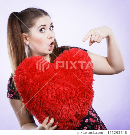 Confident woman holding heart shaped pillow Confident woman holding heart shaped pillow 135293848