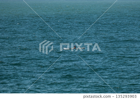 Man in a kayak paddling on open water, serene outdoor adventure or sport Man in a kayak paddling on open water, serene outdoor adventure or sport 135293903