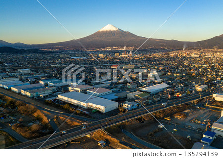 Mount Fuji and the cityscape of Fuji City at dusk as seen from the Fuji River riverbed (aerial view) 135294139