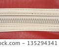 White plastic zipper on red leather texture 135294341