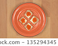 Red trout caviar canapes on orange plate 135294345