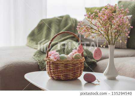 Easter Basket with Ester Eggs,  Plush Bunny and Spring Decor on White Table intoCozy Living Room 135294540