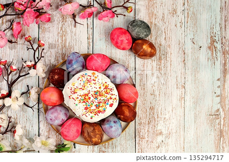 Traditional kulich and marbled Easter eggs painted with onion peel, hibiscus tea and pink matcha with sakura branches, Easter celebration concept, Easter dish ideas for home cooking 135294717