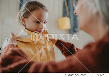 Grandmother helping granddaughter to get ready for school. Grandmother helping granddaughter to get ready for school. 135294742