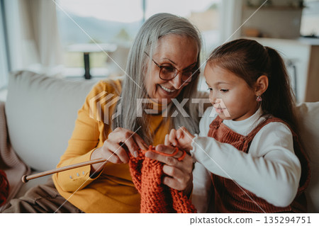 Grandmother teaching young girl how to knit, spending weekend with her. Grandmother teaching young girl how to knit, spending weekend with her. 135294751