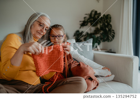 Grandmother teaching young girl how to knit, spending weekend with her. 135294752