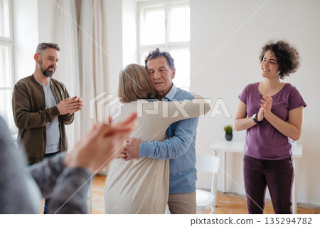 People sharing deep emotions during therapy, standing in circle with group. 135294782