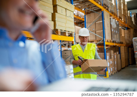 Senior woman manager and male worker working in a warehouse. Senior woman manager and male worker working in a warehouse. 135294787