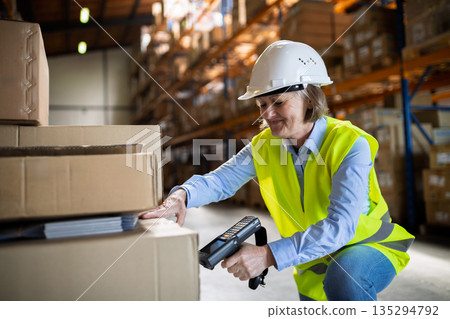 Senior warehouse woman worker working with barcode scanner. 135294792