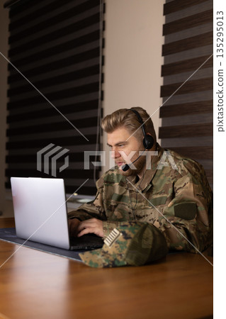 Soldier using laptop and taking notes in office 135295013