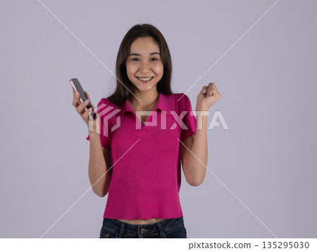 Smiling woman in pink shirt holding smartphone 135295030