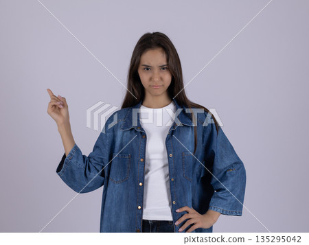 Woman in denim shirt pointing to the side 135295042