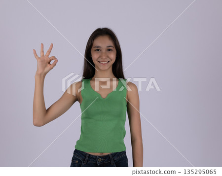 Smiling woman in green top showing OK gesture Smiling woman in green top showing OK gesture 135295065