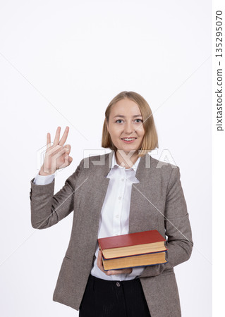 Business woman holding a stack of books and waving 135295070