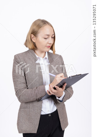 Professional woman in jacket writing on a clipboard 135295071
