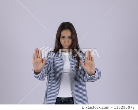 Confident woman in striped shirt showing stop gesture 135295072