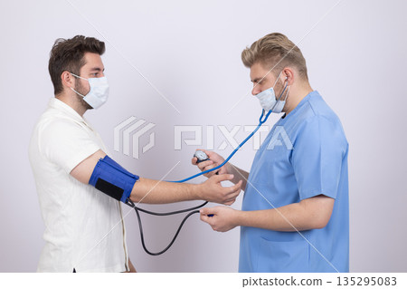 Doctor measuring blood pressure of a male patient 135295083