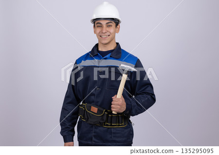 Confident builder holding large hammer near tools Confident builder holding large hammer near tools 135295095