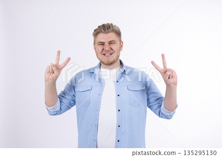 Happy man in denim shirt showing victory gesture Happy man in denim shirt showing victory gesture 135295130