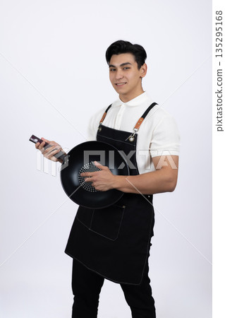 Male chef holding frying pan and kitchen spatula Male chef holding frying pan and kitchen spatula 135295168
