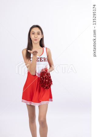 Cheerful cheerleader girl in red uniform with pom-poms Cheerful cheerleader girl in red uniform with pom-poms 135295174