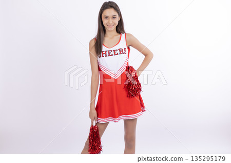 Cheerleader girl jumping with pom-poms in red uniform Cheerleader girl jumping with pom-poms in red uniform 135295179