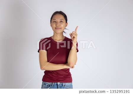 Happy woman in red shirt pointing finger up 135295191