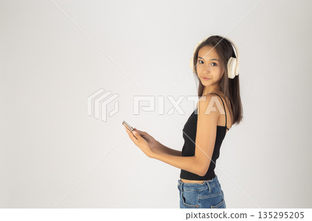 Woman in headphones looking at smartphone screen 135295205