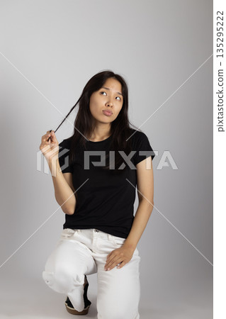 Young woman in black t-shirt twisting her hair Young woman in black t-shirt twisting her hair 135295222