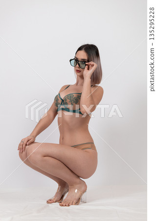 Woman in green lingerie sitting on white floor Woman in green lingerie sitting on white floor 135295228