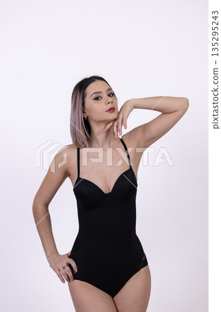 Woman in black bodysuit posing on white background 135295243