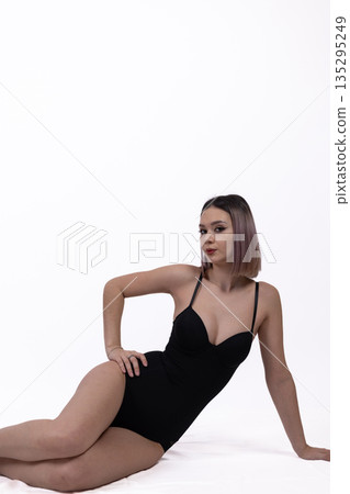 Woman in black bodysuit lying on white floor 135295249