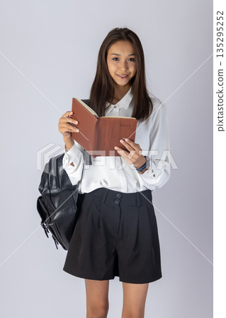 Student girl reading a book on white background Student girl reading a book on white background 135295252