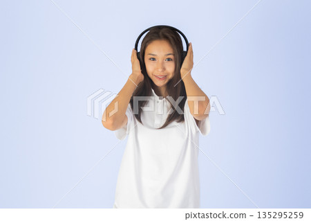 Young girl in headphones listening to music 135295259