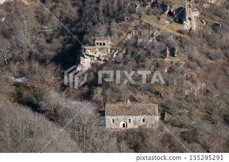 Stone houses, cave structures of Khndzoresk, Armenia, set on rocky hillside with dry vegetation, earthy tones, and a quiet rural atmosphere 135295291