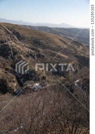 Wide canyon landscape with layered hills and rocky cliffs near Khndzoresk, Armenia, dry grass, stone textures, muted earthy colors under clear light Wide canyon landscape with layered hills and rocky cliffs near Khndzoresk, Armenia, dry grass, stone textures, muted earthy colors under clear light 135295305