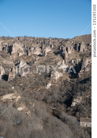 Rocky hills with caves and rugged cliffs in Khndzoresk, Armenia, under a clear blue sky, earthy tones and quiet natural atmosphere 135295308
