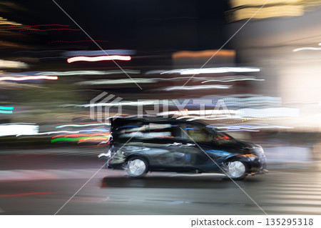Panning shot of a taxi driving through the city at night 135295318
