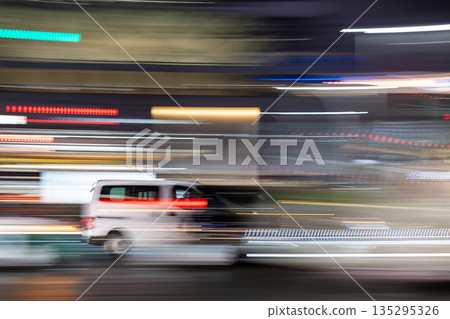 Panning shot of a white car driving through the city at night Panning shot of a white car driving through the city at night 135295326