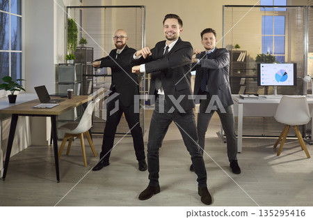 Three businessmen dance in office, celebrating success, teamwork and motivation 135295416