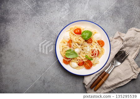 Spaghetti with cherry tomatoes and mozzarella being served on a plate with copy space 135295539