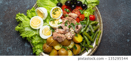 Nicoise salad with tuna, olives, green beans, tomatoes and quail eggs on a bed of lettuce Nicoise salad with tuna, olives, green beans, tomatoes and quail eggs on a bed of lettuce 135295544