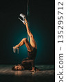 Inverted pole headstand showcasing strength and controlled balance with extended legs in glitter heels, concentrated studio atmosphere and dramatic rim lighting emphasizing core power and performance 135295712