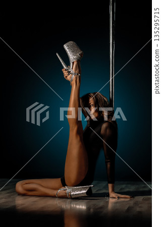 Seated pole dance pose with raised leg and glitter heels, elongated line and elegant hand placement framing editorial glamour vibe, soft rim lighting highlighting skin tone and poised expression Seated pole dance pose with raised leg and glitter heels, elongated line and elegant hand placement framing editorial glamour vibe, soft rim lighting highlighting skin tone and poised expression 135295715