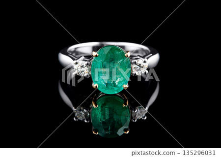 beautiful ring made of gold with precious stones emerald and diamonds on a black background 135296031